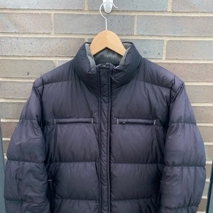 May include: A black puffer jacket with a zipper closure and a fleece lining. The jacket has a stand-up collar and a quilted design.