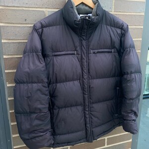 May include: A black puffer jacket with a zipper closure and a fleece-lined collar. The jacket has a quilted design and two pockets on the front.