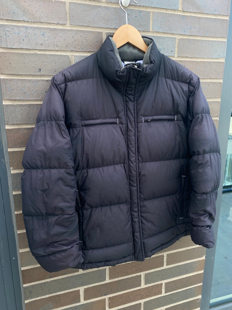 May include: A black puffer jacket with a zipper closure and a fleece-lined collar. The jacket has a quilted design and two pockets on the front.