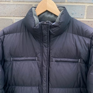 May include: Black puffer jacket with a zipper closure and a fleece lining. The jacket has a quilted design and a small logo on the chest.