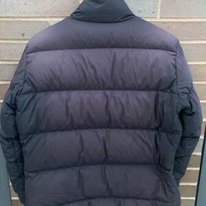 May include: A black puffer jacket with a high collar and a zipper closure. The jacket has a quilted design and is made of a lightweight material.