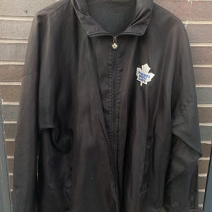May include: Black windbreaker jacket with a zip fastening and a Toronto Maple Leafs logo on the front.