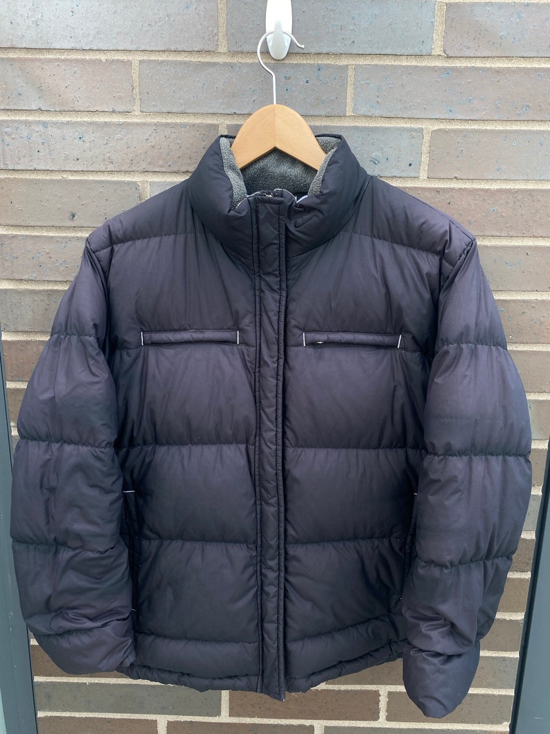 May include: A black puffer jacket with a zipper closure and a fleece lining. The jacket has a stand-up collar and a quilted design.
