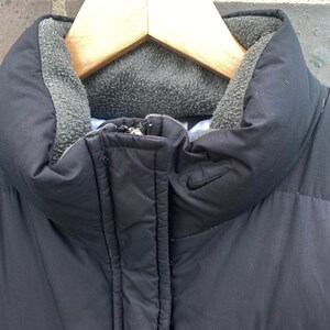 May include: Black puffer jacket with a fleece-lined collar and a Nike logo on the chest.