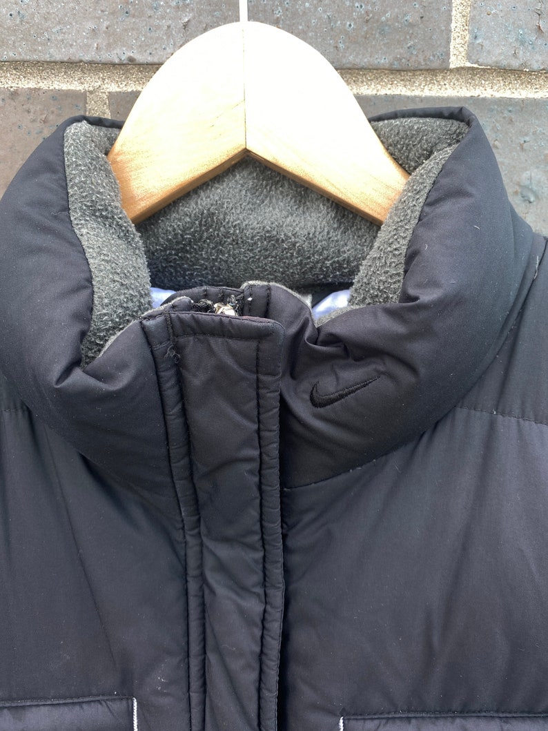 May include: Black puffer jacket with a fleece-lined collar and a Nike logo on the chest.