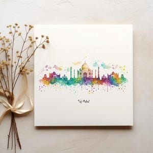 Op de afbeelding: Een aquarel schilderij van de Taj Mahal in India. Het schilderij is gemaakt in een regenboog van kleuren en heeft een gespat effect. De tekst "Taj Mahal" is onder het schilderij geschreven.