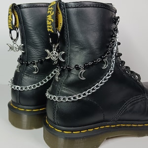 May include: Black leather boots with silver chains and crescent moon charms. The boots have a yellow tag with the word "Worn" on it.