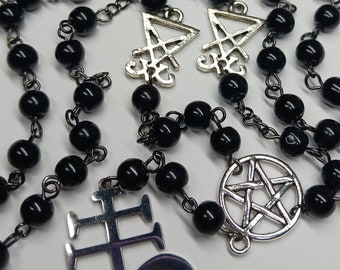 Könnte beinhalten: Schwarze Perlenkette mit silbernem Pentagramm, umgekehrtem Kreuz und anderen Symbolen.