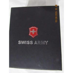 May include: A black box with the words "SWISS ARMY" in silver lettering. Above the text is a red and white emblem with a cross. The box has a textured surface.