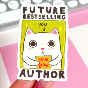 May include: A white sticker with a cartoon cat holding a sign that says "YOUR BOOK." The sticker has the text "FUTURE BESTSELLING AUTHOR" above and below the cat. The cat is inside a green rectangle.