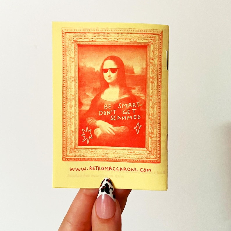 May include: A rectangular yellow booklet featuring a red-toned illustration of the Mona Lisa wearing sunglasses inside an ornate frame. The text reads BE SMART- DON'T GET SCAMMED and WWW.RETROMACCARONI.COM. The booklet has a staple binding on the right side.