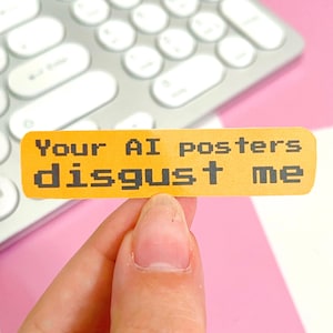 May include: A rectangular yellow sticker featuring the black pixelated text "Your AI posters disgust me" in two lines. The sticker has rounded corners and a smooth finish, displaying a bold, high-contrast design with a clear, retro-style font.