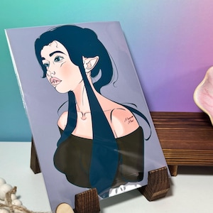 May include: A digital illustration of a woman with long blue hair and pointed ears. She is wearing a black off-the-shoulder top and has a small tattoo on her shoulder that says "Amanda Mai".