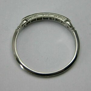 May include: A silver band ring with a row of small diamonds set in a channel setting.