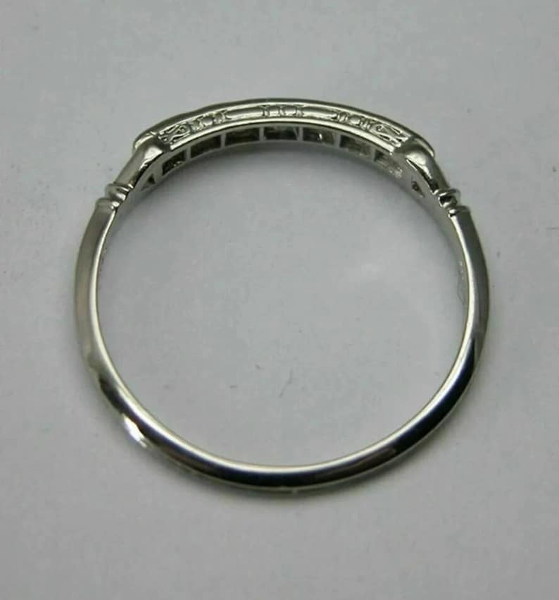 May include: A silver band ring with a row of small diamonds set in a channel setting.