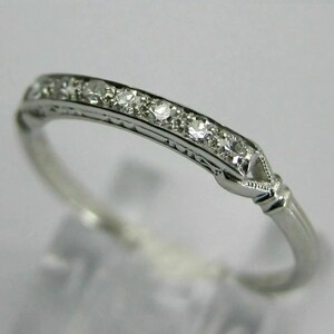 May include: A delicate silver band ring with a row of small, sparkling diamonds set in a simple, elegant design.