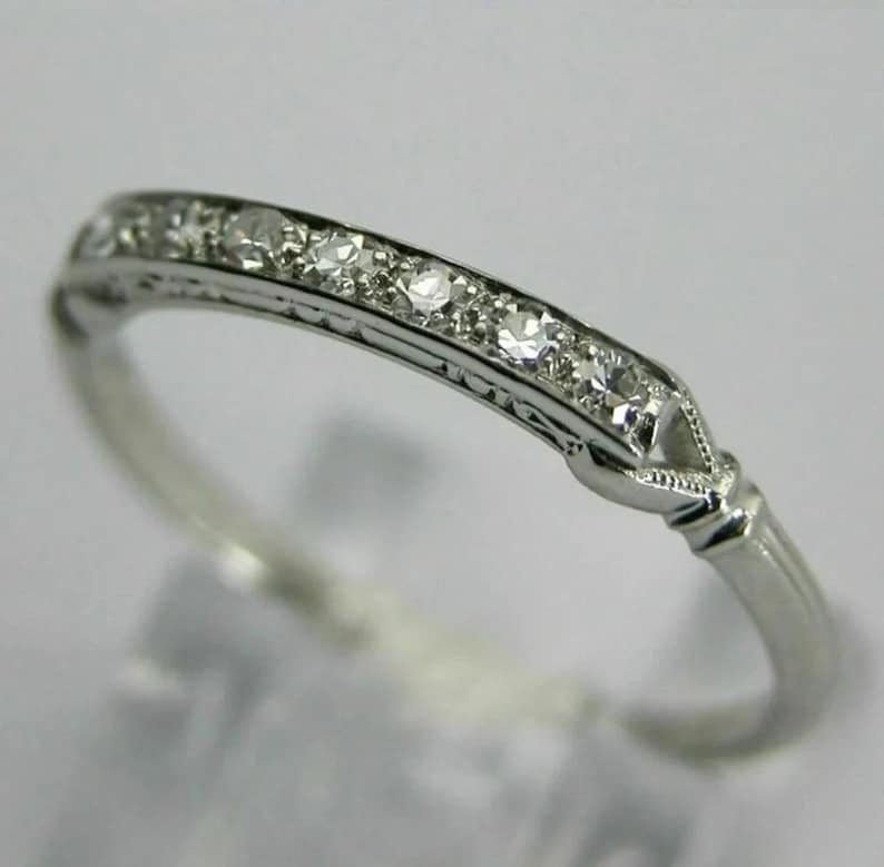 May include: A delicate silver band ring with a row of small, sparkling diamonds set in a simple, elegant design.