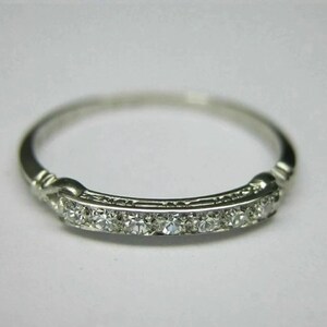 May include: A delicate silver band ring with a row of small diamonds set in a channel setting.