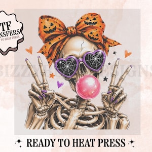 May include: A graphic illustration of a skeleton wearing a large orange bow with jack-o'-lantern faces, purple heart-shaped sunglasses with spiderweb lenses, and blowing a pink bubblegum bubble. The skeleton makes peace signs with both hands.