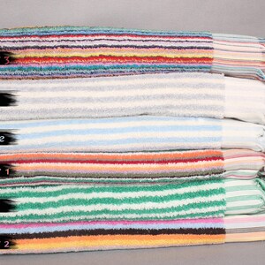 May include: A stack of six striped towels in various colors, including green, gray, light blue, and multicolor. The towels are folded and stacked on top of each other. The top towel is labeled "Multicolor 3", the second towel is labeled "Gray", the third towel is labeled "Light Blue", the fourth towel is labeled "Multicolor 1", the fifth towel is labeled "Green", and the bottom towel is labeled "Multicolor 2".