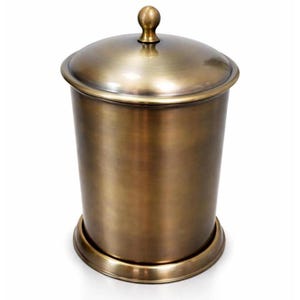 May include: A cylindrical canister with a brushed antique brass finish. The container features a matching domed lid topped with a small spherical knob and a circular base rim. The metal surface displays a smooth, metallic sheen throughout the body.