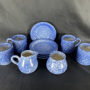 May include: A blue and white speckled tea set with four cups, four saucers, a creamer, and a sugar bowl.