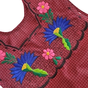 May include: Red and white checked fabric with embroidered flowers in pink, blue, green, and yellow. The flowers are in a floral pattern.