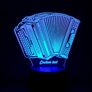 Puede incluir: Una luz nocturna LED azul con forma de acordeón con el texto "Custom text" en la base.