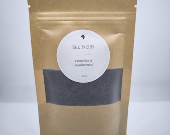 May include: A brown paper bag with a clear window displaying black granules. A white circular label reads "SEL NOIR" with "Protection & Bannissement" below. The bag is sealed at the top.