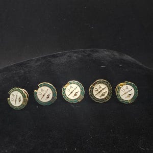 May include: Five round pins with gold-colored rims and green and white enamel details. Each pin features the letters "UA" and a graphic of a wrench and a hammer. The pins are numbered 30, 45, and 50.