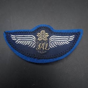 May include: A blue felt patch with white wings and a gold embroidered maple leaf and the letters "SAL" in the center.