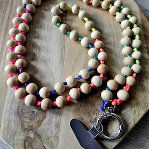 May include: Wooden bead lanyard with a rainbow of colored cord. The lanyard has a silver-colored clasp and a black metal clip. The beads are light brown and the cord colors include pink, orange, yellow, green, blue, and purple.