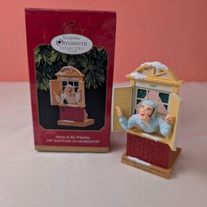 May include: A 1997 Hallmark Keepsake Ornament titled Away to the Window, featuring a figure in a light blue nightshirt and cap leaning out of a window with open shutters. The ornament is displayed next to its original red box with white text.