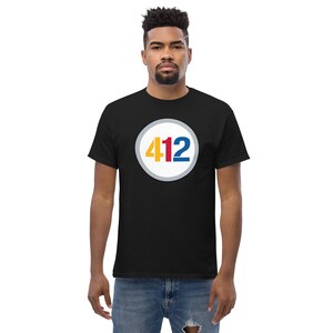 May include: Black t-shirt with a white circle containing the number 412 in red, yellow, and blue.