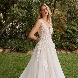 Bride wearing a romantic whimsical flower lace wedding dress in an outdoor garden wedding with detachable long sleeves and a long gown train