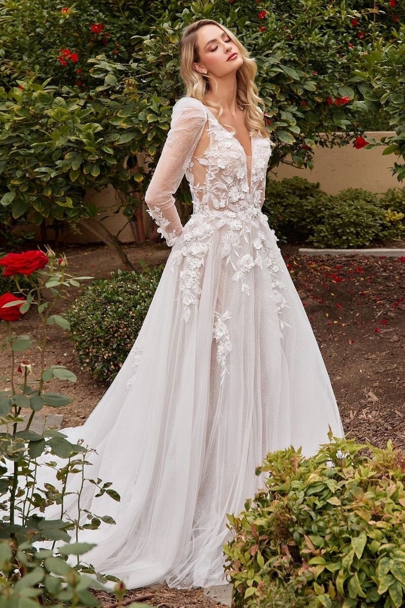 Bride wearing a long sleeve a line wedding dress with 3d flowers and romantic glitter tulle with a long gown train