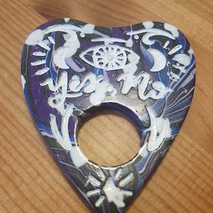 large galaxy themed planchette, hand made polymer clay marbled black, purple and blue Ouija board planchette, with eye moon and stars motif