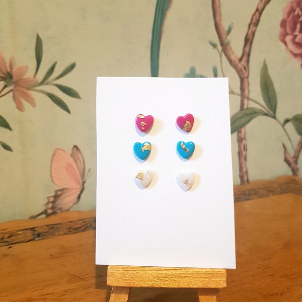 Set of 3 trans pride heart earrings, polymer clay heart shaped studs in pink, blue and white decorated with gold leaf.