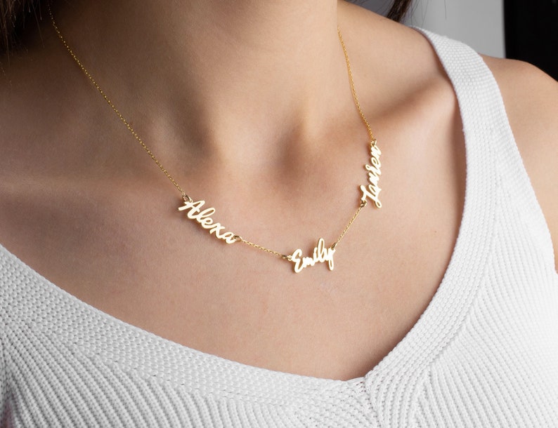 May include: Gold necklace with three names, "Alexa", "Emily", and "Lauren", spelled out in cursive.