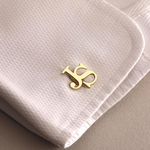 Könnte beinhalten: Goldene Manschettenknöpfe mit den ineinander verschlungenen Initialen "JS".