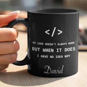 a person holding a black coffee mug on a table