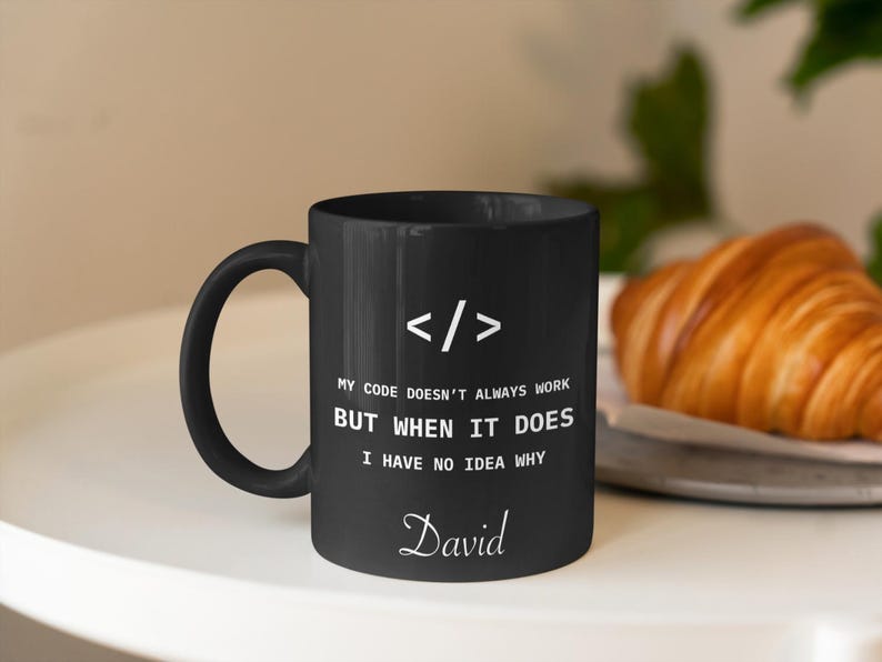 a black coffee mug sitting on top of a white table