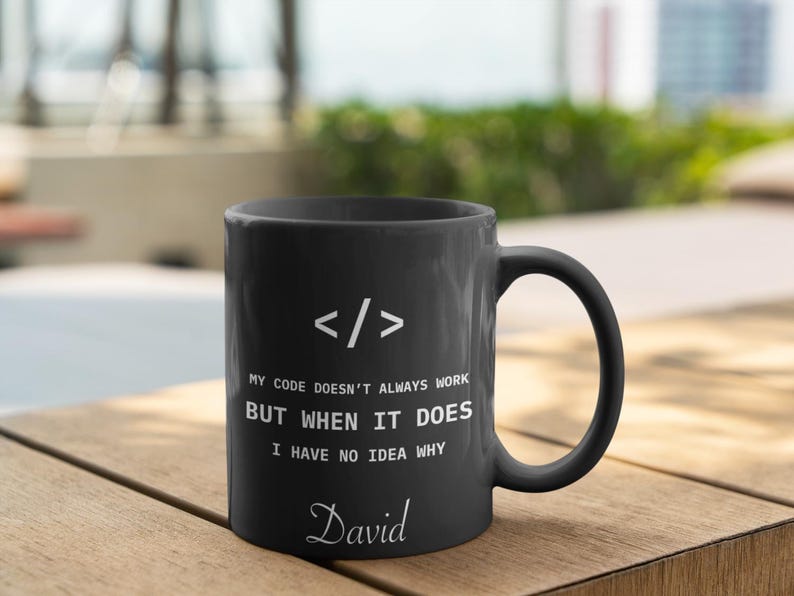 a black coffee mug sitting on top of a wooden table