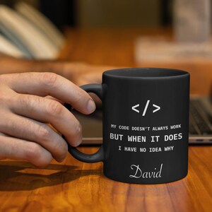 a person is holding a coffee mug in front of a laptop