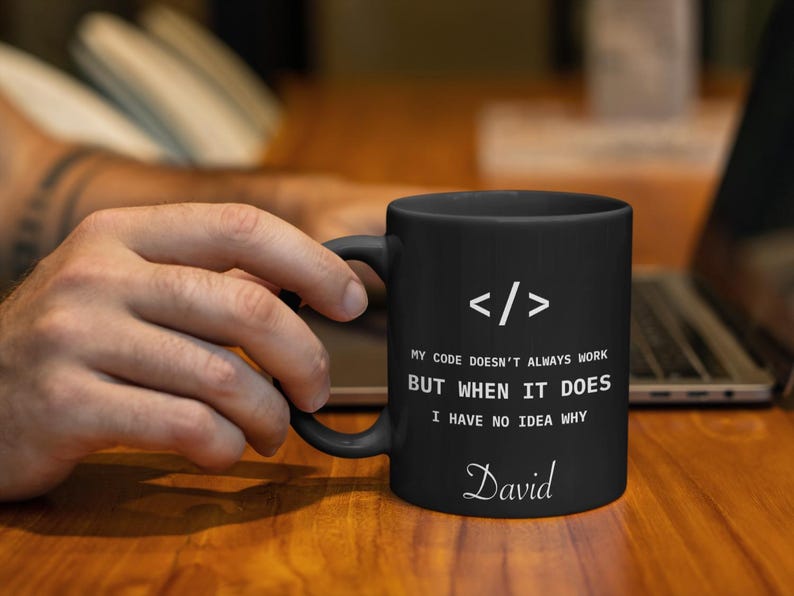 a person is holding a coffee mug in front of a laptop