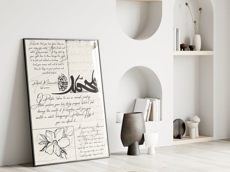 May include: A black and white Islamic calligraphy print with a floral design. The print features Arabic text and a quote from the Prophet Muhammad. The print is framed in a black frame and is hanging on a white wall.
