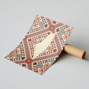 May include: A beige card with a red, blue, and white geometric pattern. The pattern is reminiscent of traditional embroidery. The card is rolled up and partially visible.