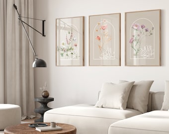 May include: Three framed prints with floral illustrations and Arabic calligraphy. The prints are in a light brown frame with a white mat. The prints are hanging on a white wall.