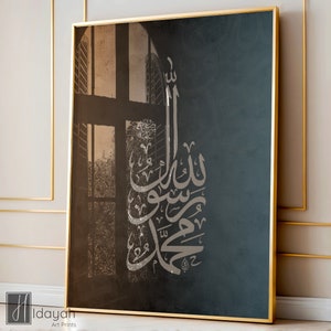 May include: A black and white canvas print with a gold frame. The print features a window with a view of trees and a silver Arabic calligraphy design. The calligraphy reads "Allah is the Light of the Heavens and the Earth".