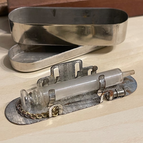Seringue ancienne en verre avec aiguille, chaînette en laiton, stérilisateur, et boîte en métal / Instrument médical vintage de collection